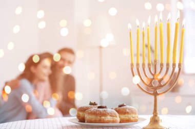 Menorah ve çörekler mutlu aile tablosunun üzerinde Hanuka 'yı evde kutluyorlar.