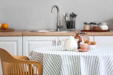 Çaydanlık, fincanlar ve kekler mutfaktaki masada.