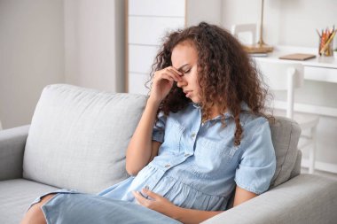 Stresli hamile Afro-Amerikan kadın evde.