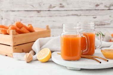 Hafif ahşap zemin üzerinde havuç suyu dolu Mason kavanozları.