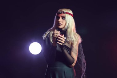 Karanlık arka planda mumu olan genç cadı.