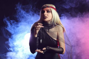 Genç cadı karanlık arka planda ayin yapıyor.