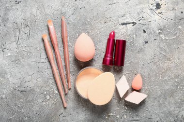 Gri arka planda dekoratif kozmetik ve makyaj süngerleri