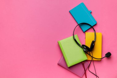 Renk arkaplanı üzerine not defterleri olan kulaklık