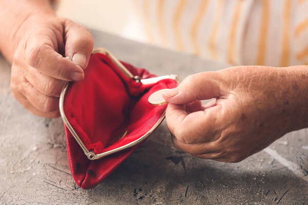 Senior woman with wallet and coins at table. Concept of pension