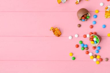 Lezzetli çikolata yumurtası ve renkli ahşap arka planda şekerler.