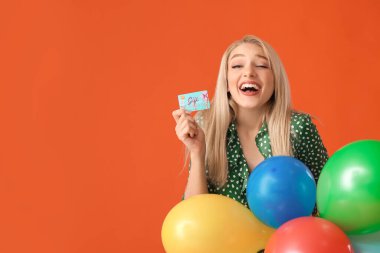 Beautiful young woman with gift card and balloons on color background clipart
