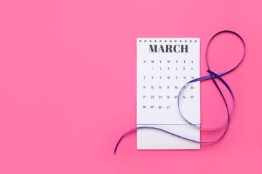 Renkli arka planda takvim ve menekşe kurdelesi. Uluslararası Kadınlar Günü kutlamaları