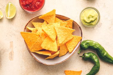 Hafif arka planda lezzetli nachos ve soslu tabak.