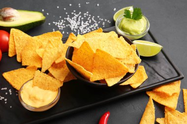 Koyu arkaplanda lezzetli cips ve soslar.