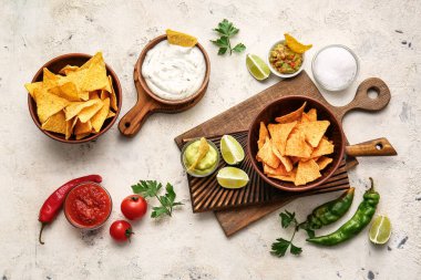 Hafif arka planda lezzetli nachos ve soslu kaseler.