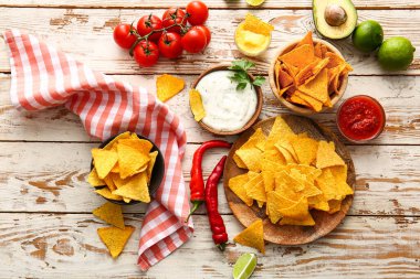 Hafif ahşap arka planda lezzetli nachos ve soslu tabaklar