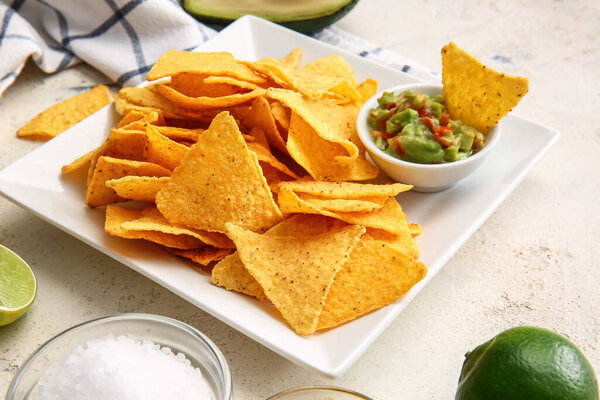 Plate with tasty nachos and sauce on light background, closeup