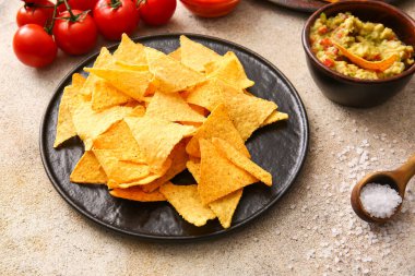 Hafif arka planda lezzetli nachos ve guacamole soslu tabak.