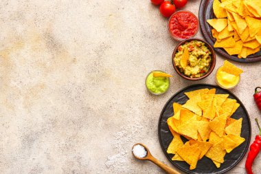 Hafif arka planda lezzetli nachos ve soslu tabaklar.