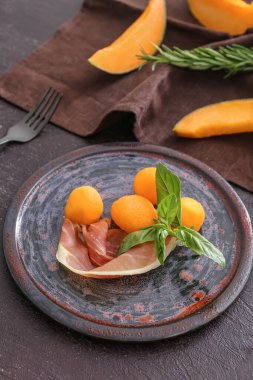 Lezzetli kavunlu tabak ve koyu arkaplanda jambon.