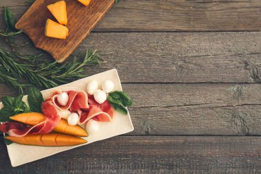 Lezzetli kavun, mozzarella ve ahşap kaplama jambonlu tabak.