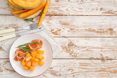 Lezzetli kavun tabağı ve ahşap arka planda jambon.