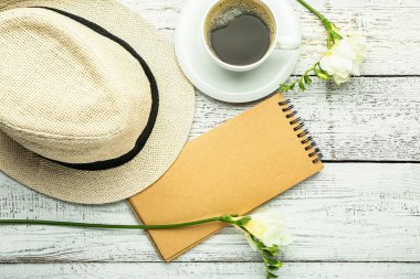 Beyaz ahşap arka planda şapkası ve kahvesi olan boş bir defter.