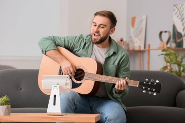 Genç adam evde online müzik dersleri alıyor.