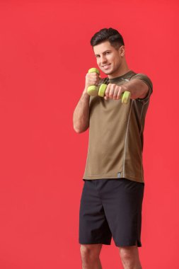 Renkli arka planda dambılları olan sportif genç adam eğitimi.