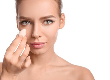 Beyaz arka planda makyaj süngeri olan güzel bir genç kadın.