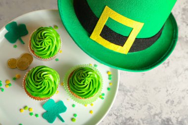 Aziz Patrick Günü için lezzetli kekler ve grunge arka planda leprikon şapkalı tatlı standı.