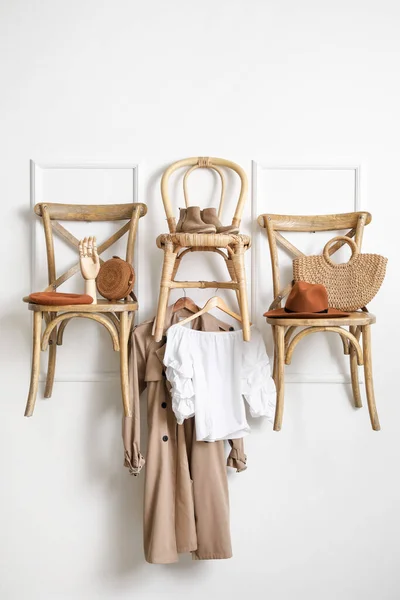 Chairs with clothes and accessories hanging on light wall in room