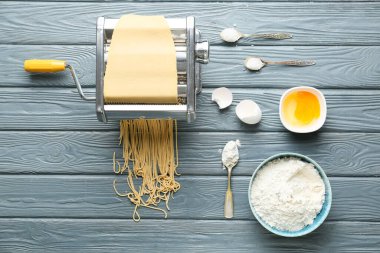 Hamurlu makarna makinesi ve ahşap arka planda malzemeler