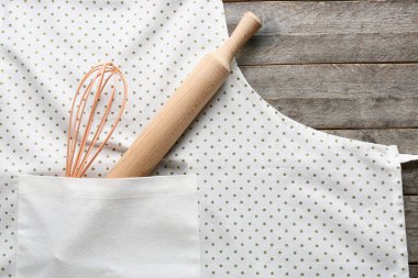 Ahşap arka planda temiz önlük ve mutfak aletleri, yakın plan.