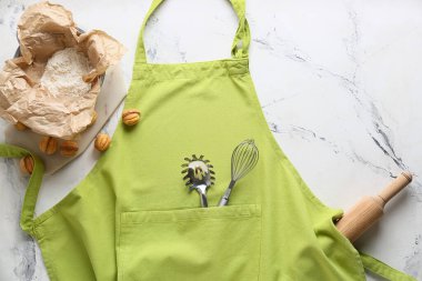 Önlük, mutfak gereçleri ve arka planda un.