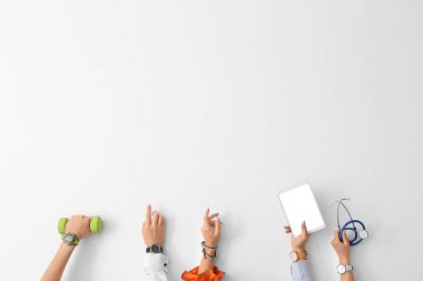 Kol saatli eller, dambıl, tablet bilgisayar ve arka planda steteskop.