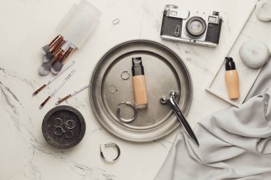 Makyaj malzemeleri, aksesuarlar ve arka planda fotoğraf makinesi.