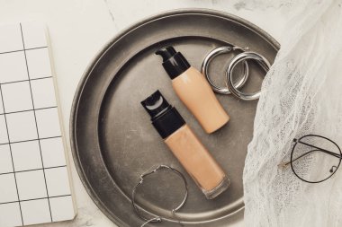 Makyaj malzemeleri ve hafif arka planda aksesuarlar olan tepsi.