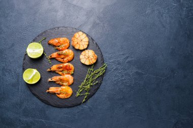 Koyu arkaplanda lezzetli karidesli tahta tabak.