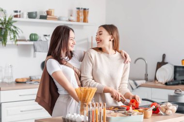 Genç lezbiyen çift mutfakta yemek pişiriyor.