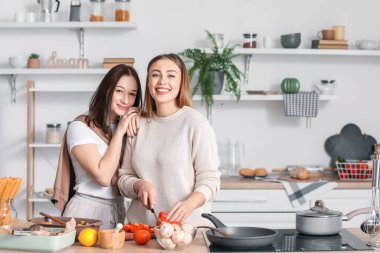 Genç lezbiyen çift mutfakta yemek pişiriyor.