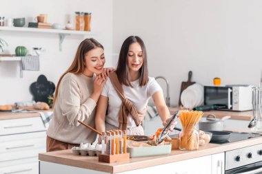 Genç lezbiyen çift mutfakta yemek pişiriyor.