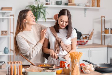 Genç lezbiyen çift mutfakta yemek pişiriyor.