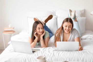 Evde dizüstü bilgisayarları olan genç lezbiyen çift.