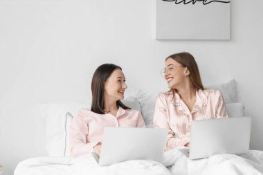 Evde dizüstü bilgisayarları olan genç lezbiyen çift.