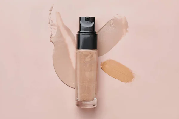 Bottle of makeup foundation and samples on color background