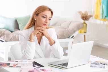 Stüdyoda çalışan dizüstü bilgisayarı olan kadın moda tasarımcısı.