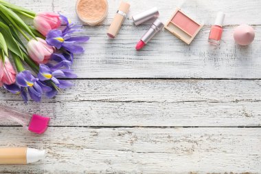 Ahşap arka planda kozmetik ve bahar çiçekleri