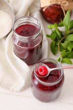 Hafif arka planda ahududu reçeli olan cam kavanozlar