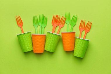 Renkli arka planda plastik çatallar ve bardaklar