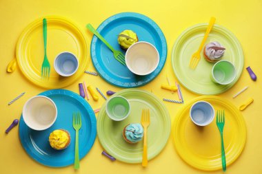 Renkli arka planda plastik masa takımı ve kekler