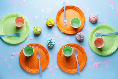 Renkli arka planda plastik masa takımı ve kekler
