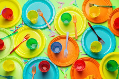 Renkli arkaplanda plastik sofra takımı ve konfeti