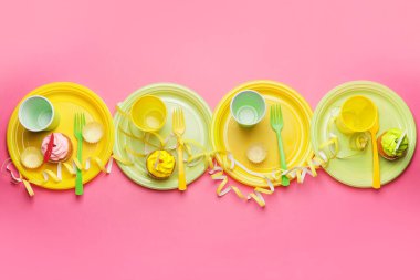 Renkli arka planda plastik masa takımı ve kekler